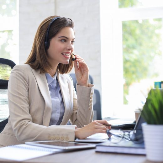 Beautiful smiling call center worker in headphones is working at modern office.